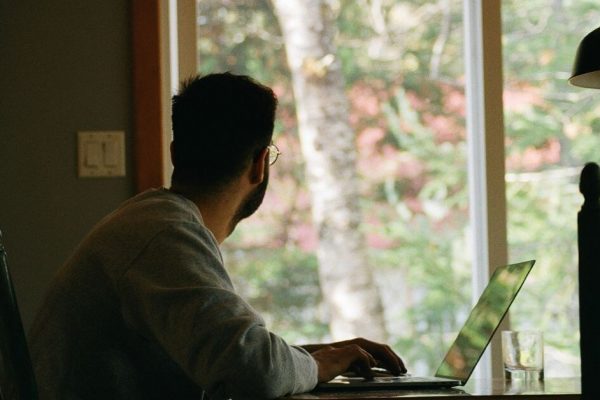 man sat at desk looking out a window