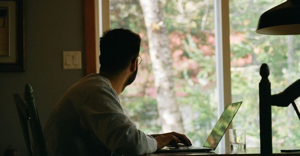 man sat at desk looking out a window